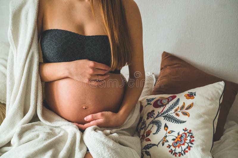 Attractive pregnant woman is sitting in bed and holding her belly. Last months of pregnancy. stock images Attractive pregnant woman is sitting in bed and holding her belly. Last months of pregnancy. stock images