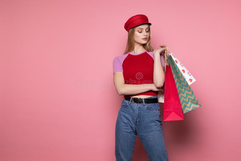Attractive pretty seriously young female model in stylish red hat standing against pink wall royalty free stock images Attractive pretty seriously young female model in stylish red hat standing against pink wall royalty free stock images
