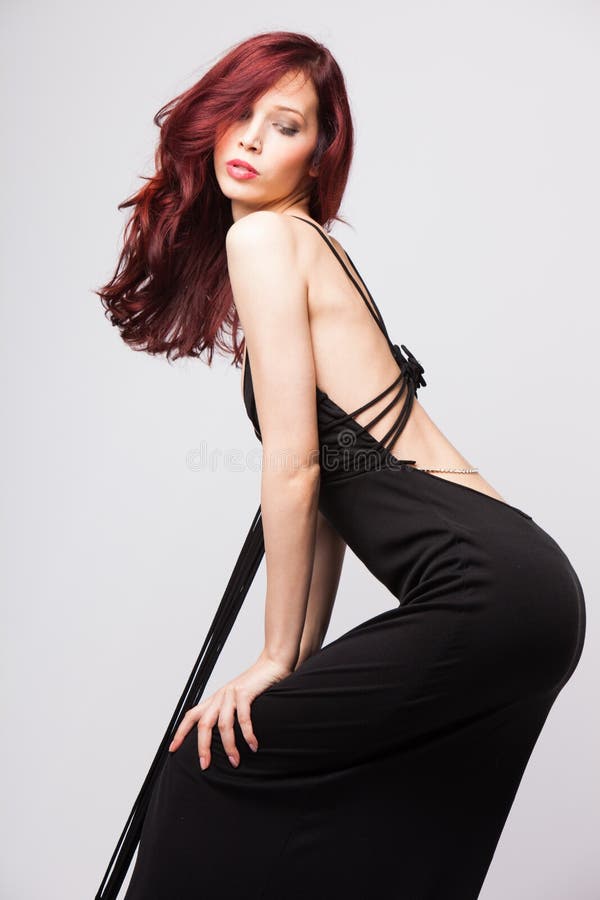 Attractive red-haired girl in long evening black dress