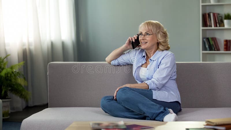 Attractive senior woman sitting on couch and calling daughter, communication stock image Attractive senior woman sitting on couch and calling daughter, communication stock image