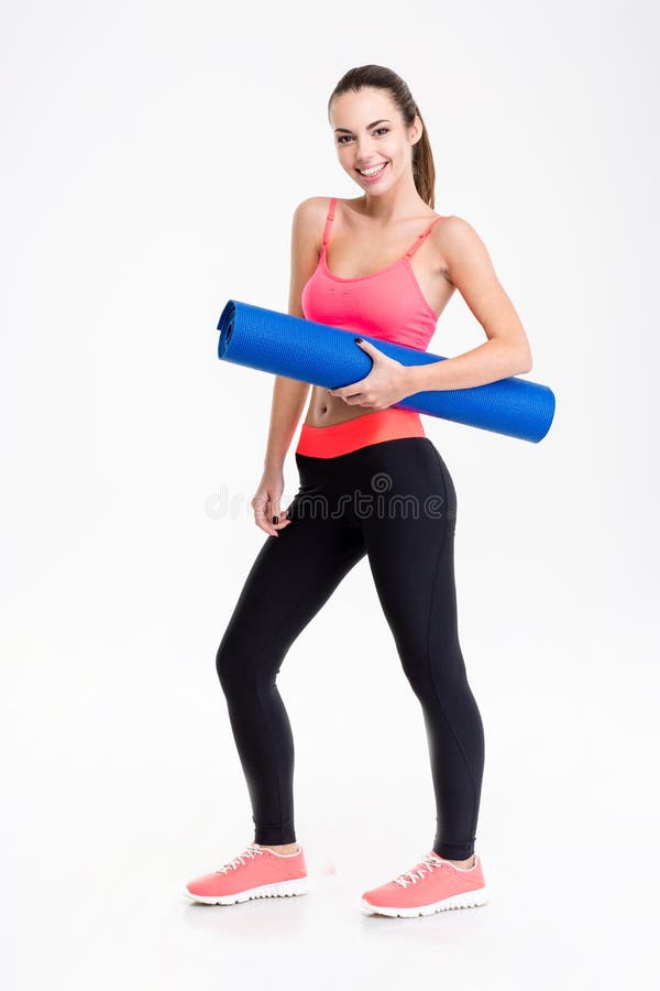 Young attractive woman in sportswear holding yoga mat and smiling