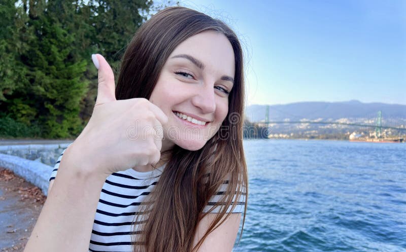 Attractive Ukrainian woman shows thumb up, like gesture. Photo of positive woman in yellow shirt against the background stock photo