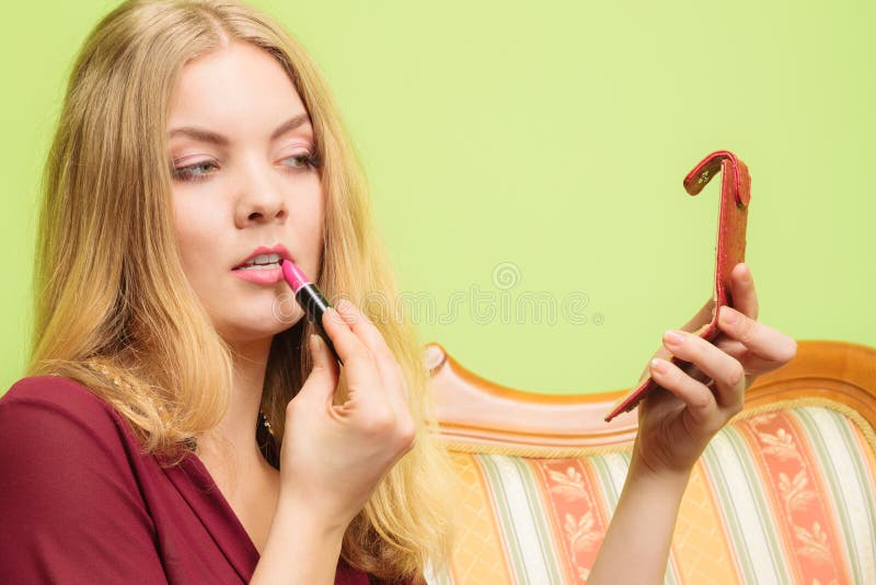 Attractive woman applying lipstick. Make up.