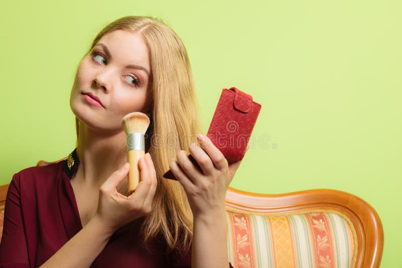 Attractive woman applying make up with brush.