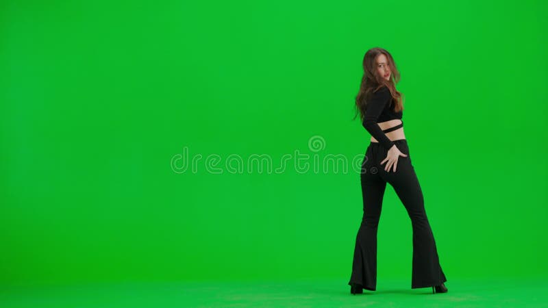 Attractive woman dancing heels dance on green screen chroma key background in a studio. Black sexy costume, high heels