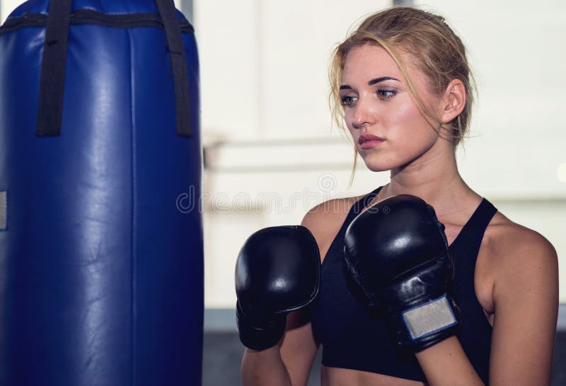 An attractive woman guarding and punching on a sand bag at the g royalty free stock photos An attractive woman guarding and punching on a sand bag at the g royalty free stock photos