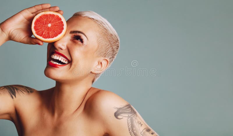 Attractive woman holding a grapefruit and smiling