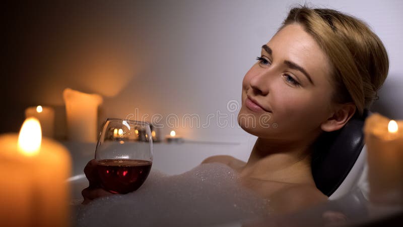 Attractive woman lying in bath with foam bubbles and candles, drinking wine royalty free stock photography Attractive woman lying in bath with foam bubbles and candles, drinking wine royalty free stock photography