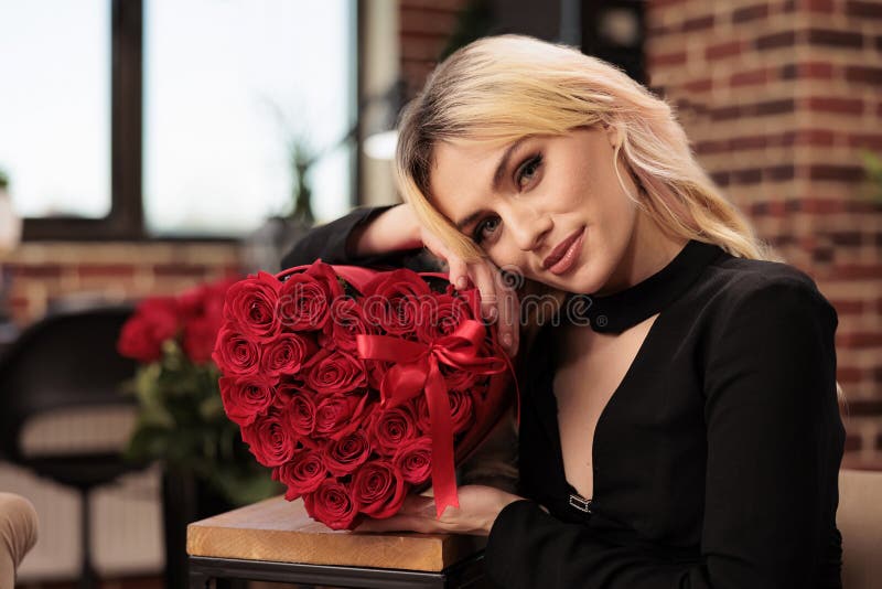 Attractive woman posing with red roses in heart shaped box