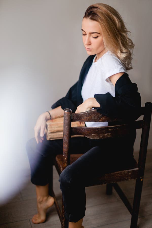Attractive woman sitting with vintage books on the chair. Education. royalty free stock photography Attractive woman sitting with vintage books on the chair. Education. royalty free stock photography