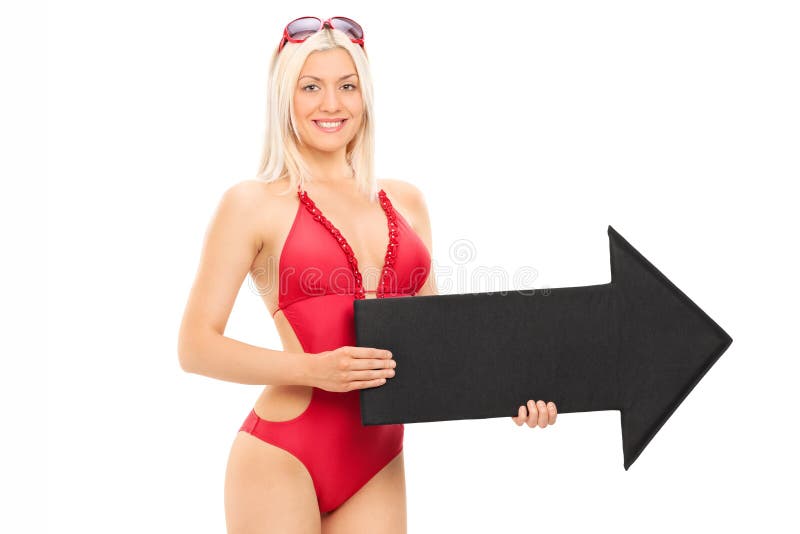 Attractive woman in swimsuit holding a big black arrow pointing right isolated on white background. Attractive woman in swimsuit holding a big black arrow pointing right isolated on white background