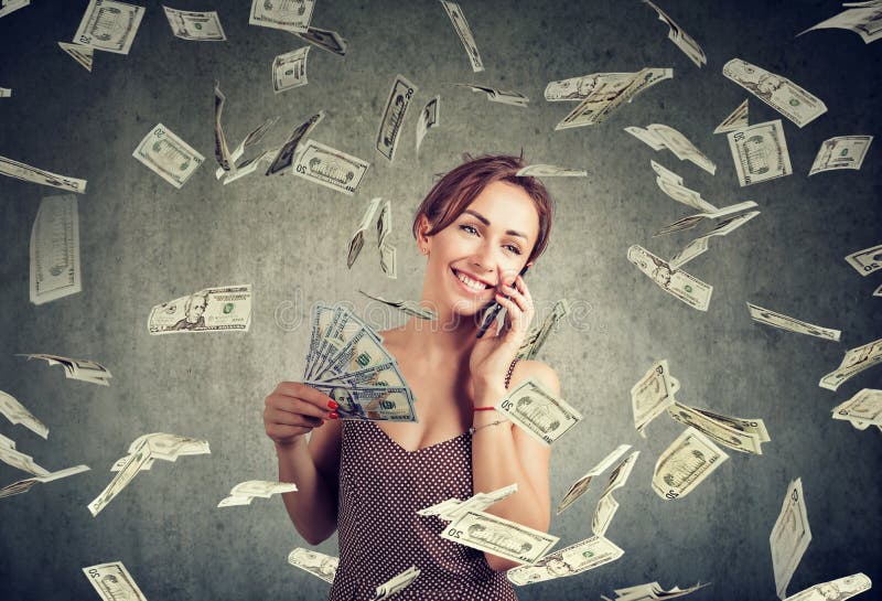Attractive woman talking on a smartphone holding money, cashback under dollar rain stock image Attractive woman talking on a smartphone holding money, cashback under dollar rain stock image