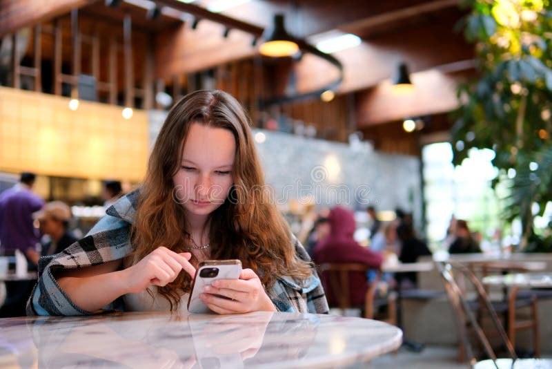 Attractive Woman typing text message on smart phone in a cafe with a coffee stock images
