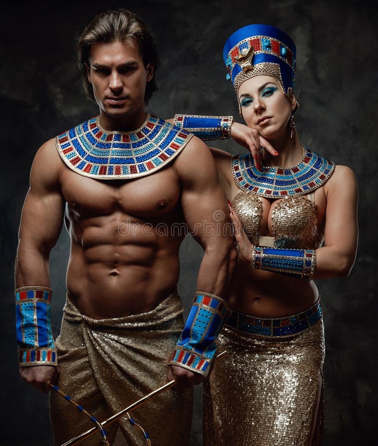 Two people in egyptian costumes, posing in the studio wit the dark background