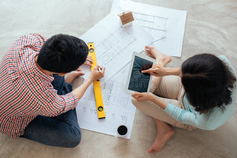 Attractive young asian adult couple looking at house plans.