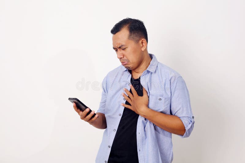 Attractive young Asian man reading texting chatting on his phone, bad news, sad crying expression