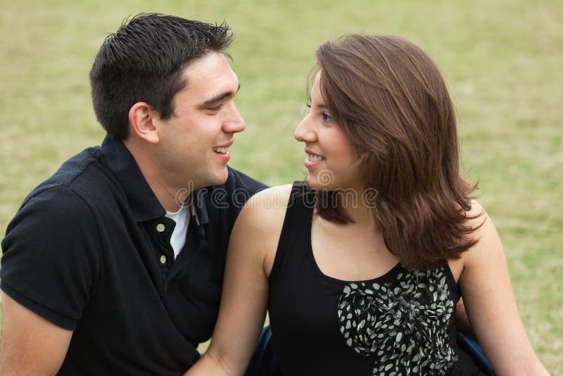 Attractive young multicultural couple in a affectionate pose outdoors in a park setting. Attractive young multicultural couple in a affectionate pose outdoors in a park setting.