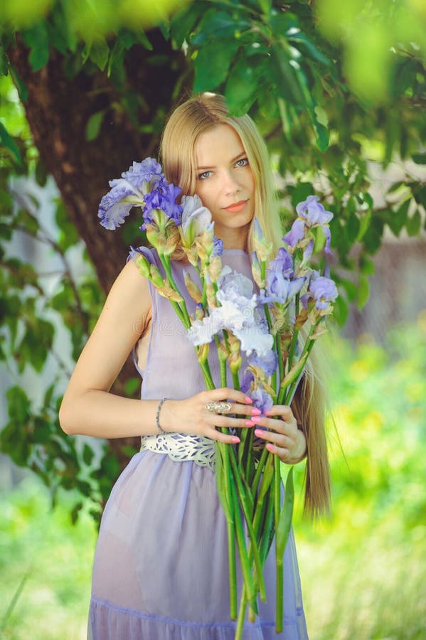 Atraktivní mladý blondýnka vlasy přírodní vonící modrý purpurová kosatec květiny na venku, měkkost měkkost na příroda.