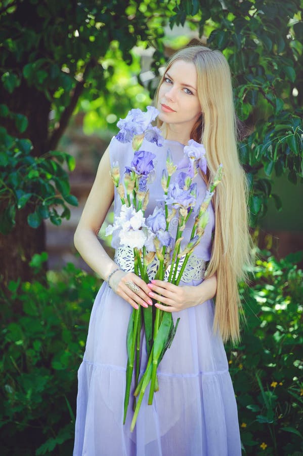 Atraktivní mladý blondýnka vlasy přírodní vonící modrý purpurová kosatec květiny na venku, měkkost měkkost na příroda.