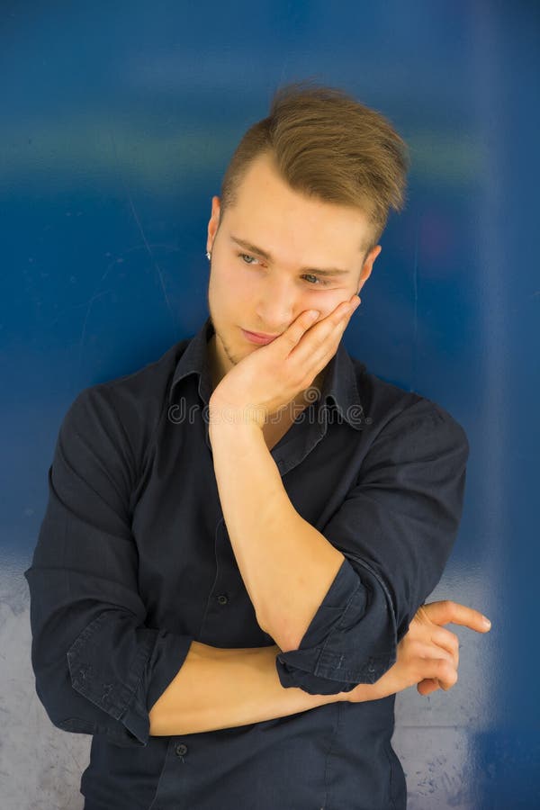 Attractive Young Man Thinking, Looking Up with Hand on His Cheek Stock