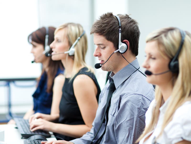 Attractive young man working in a call center with his colleagues