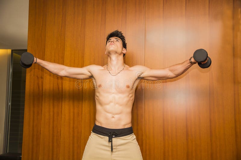 Attractive young man working out with dumbbells at
