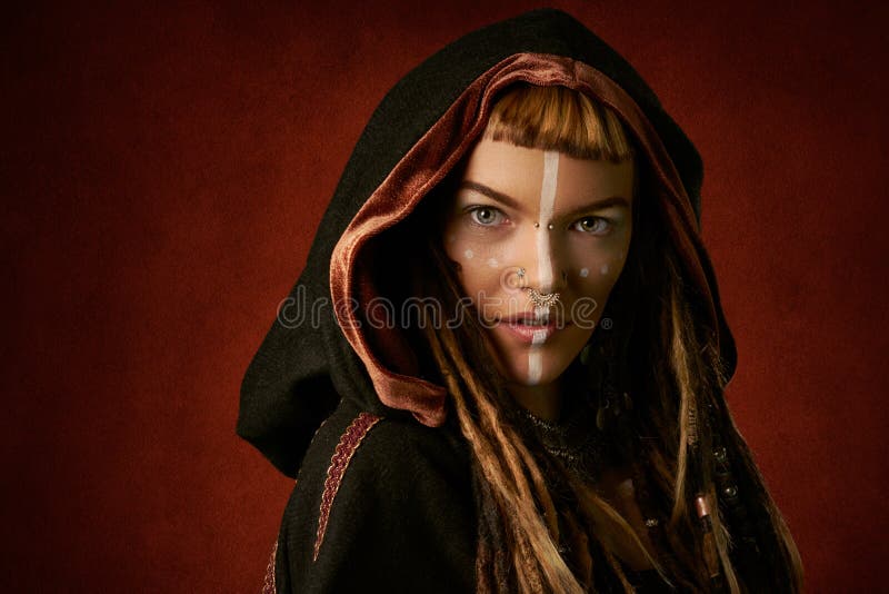 Attractive, young, stylish woman in a black, tribal hood on red background stock photo Attractive, young, stylish woman in a black, tribal hood on red background stock photo