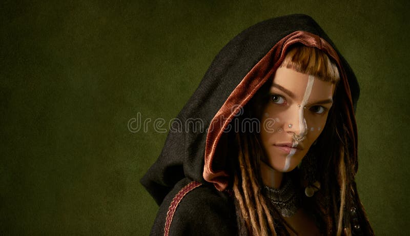 Beautiful, young, stylish woman in a black, tribal hood on green background royalty free stock image Beautiful, young, stylish woman in a black, tribal hood on green background royalty free stock image