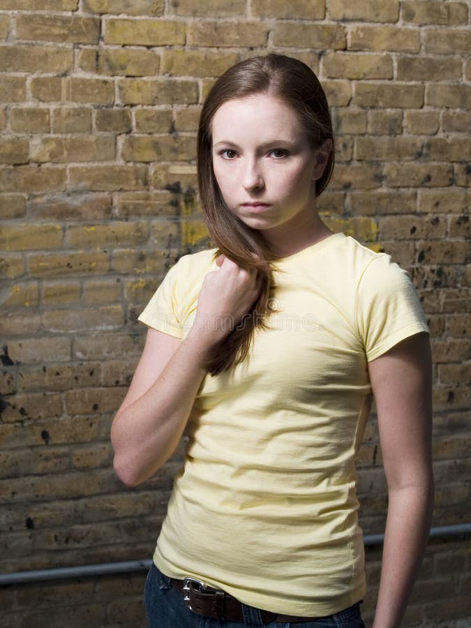 Half body portrait of attractive young woman with brick wall in background.