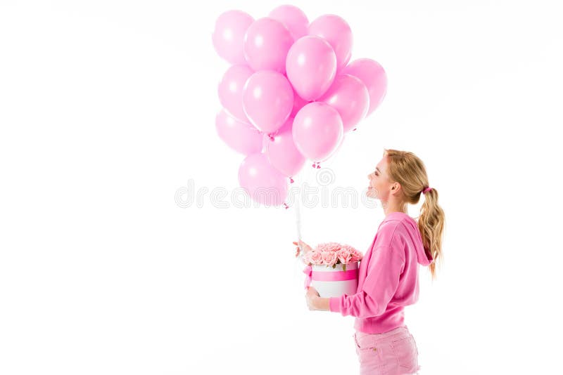 Attractive young woman dressed in pink holding balloons with flowers