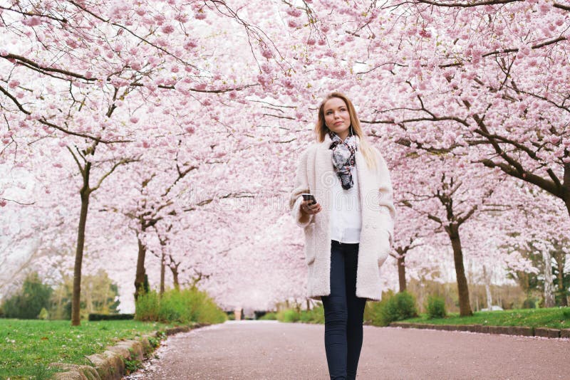 Attractive young woman enjoying music at spring blossom garden stock photo Attractive young woman enjoying music at spring blossom garden stock photo