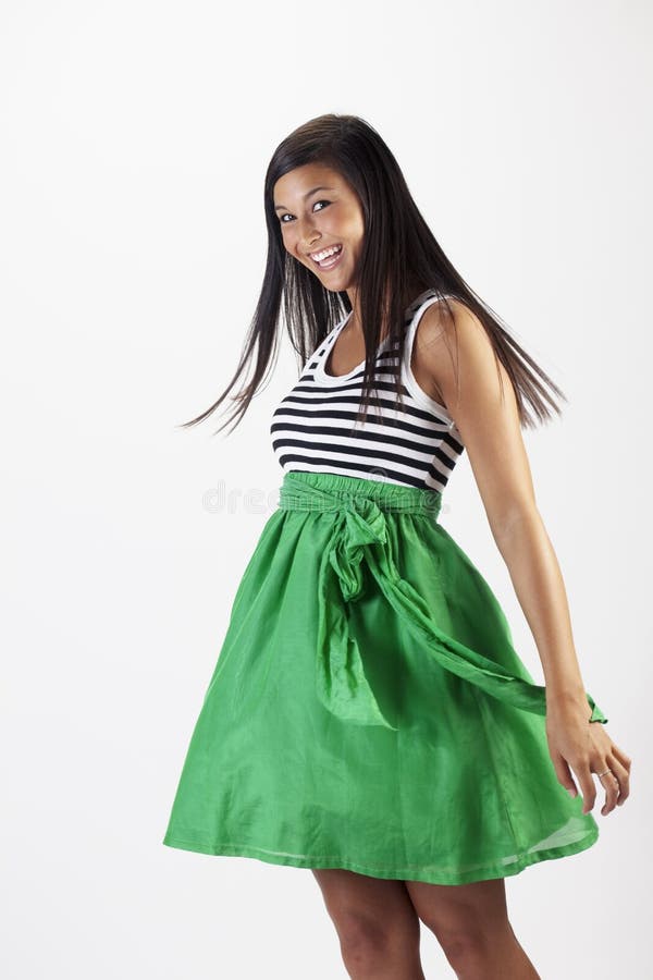 Beautiful young Asian woman models a green skirt. She is smiling toward the camera and has her hair in motion. Vertical shot. Beautiful young Asian woman models a green skirt. She is smiling toward the camera and has her hair in motion. Vertical shot.