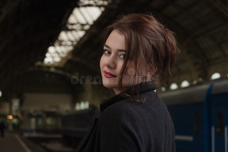 Attractive young woman millenial in black clothes and a hat and glasses at the railway station next to the train royalty free stock photos Attractive young woman millenial in black clothes and a hat and glasses at the railway station next to the train royalty free stock photos