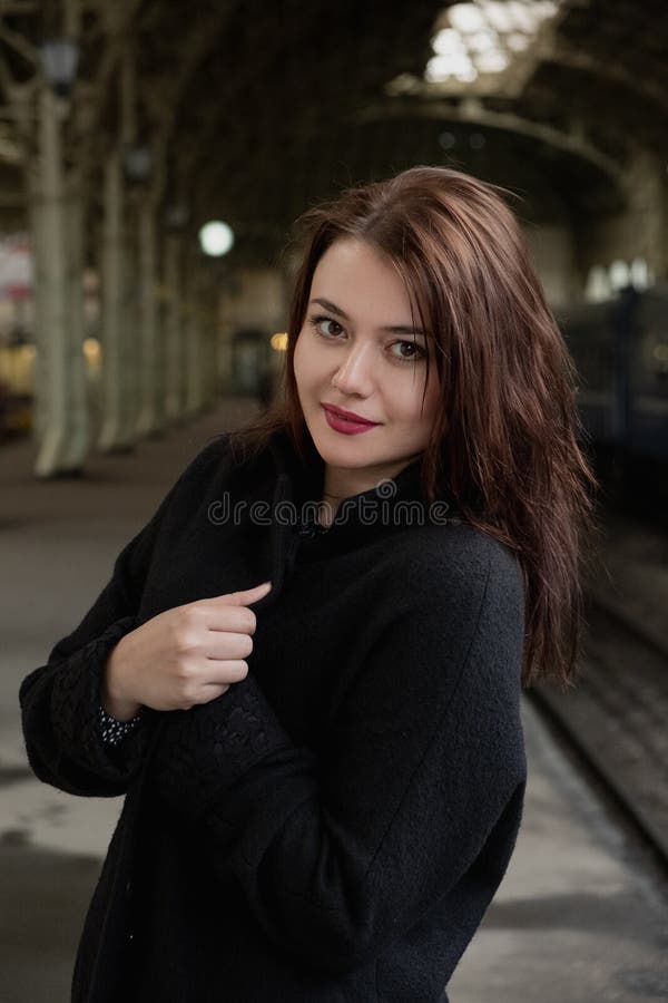 Attractive young woman millenial in black clothes and a hat and glasses at the railway station next to the train stock photo Attractive young woman millenial in black clothes and a hat and glasses at the railway station next to the train stock photo