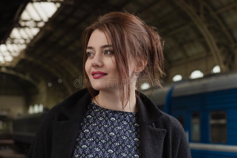 Attractive young woman millenial in black clothes and a hat and glasses at the railway station next to the train stock photography Attractive young woman millenial in black clothes and a hat and glasses at the railway station next to the train stock photography