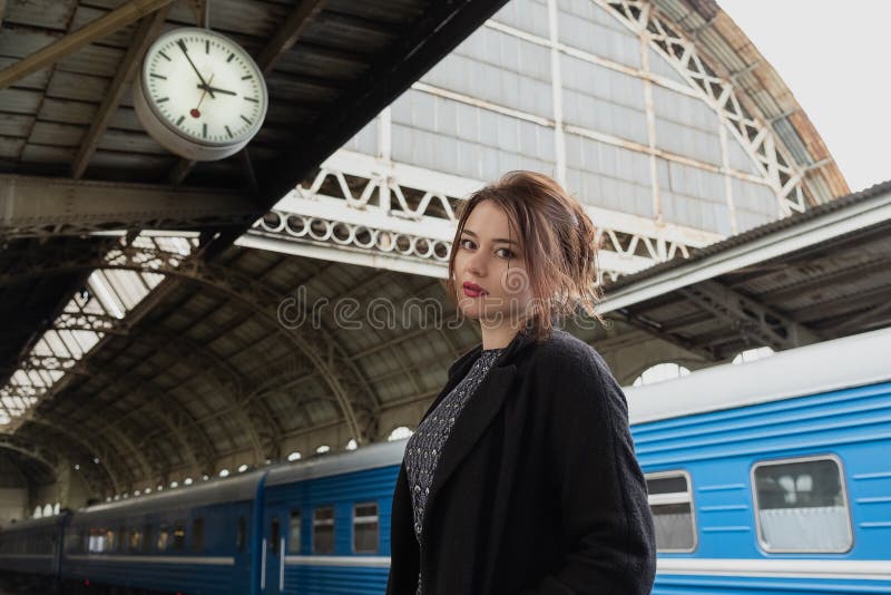 Attractive young woman millenial in black clothes and a hat and glasses at the railway station next to the train royalty free stock image Attractive young woman millenial in black clothes and a hat and glasses at the railway station next to the train royalty free stock image