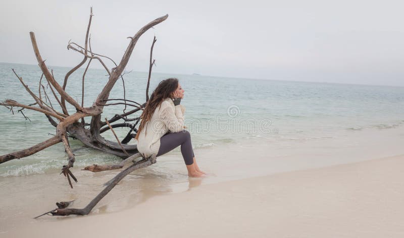 Attractive young woman in sweater sitting on beach. royalty free stock photos Attractive young woman in sweater sitting on beach. royalty free stock photos