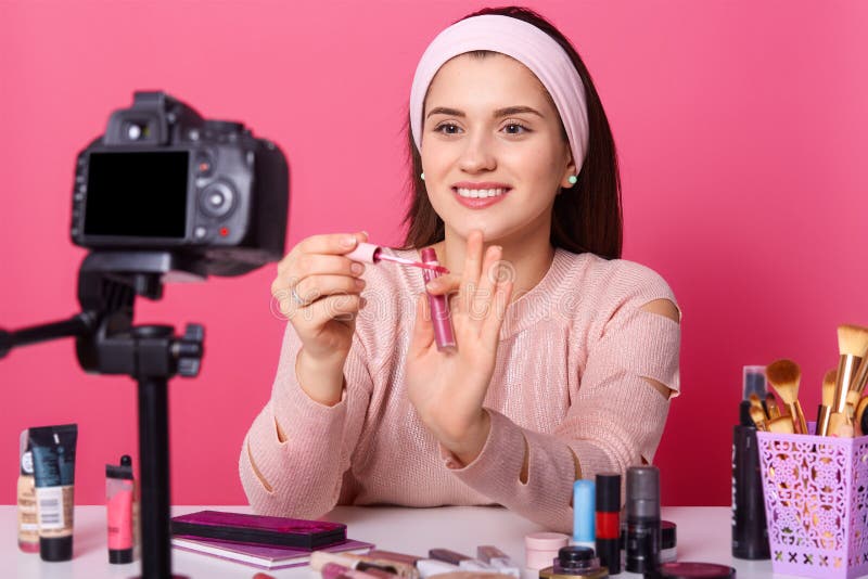 Attractive Young Woman Tests Some Beauty Products and Shows Lip Gloss in  Her Blog. Beauty Vlogger Sits in Front of Camera and Hods Stock Photo -  Image of camera, care: 140905778