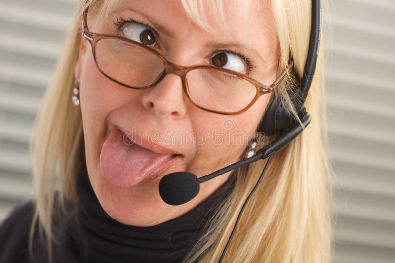 Attractive-goofy businesswoman is bored or exasperated while she talks on her phone headset. Attractive-goofy businesswoman is bored or exasperated while she talks on her phone headset.