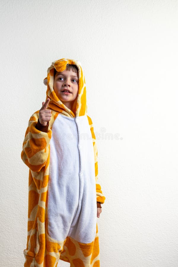 Attraktiv barnpojke klädd i giraffe pyjamas som står över isolerad vit bakgrund och pekar med fingret uppåt och arkivbilder