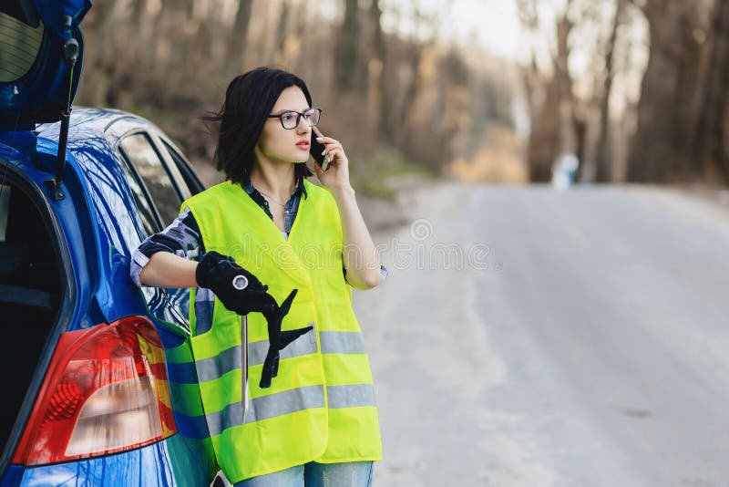 attraktiv flicka som talar vid telefonen nära bilen på vägen i säkerhetsstålar royaltyfri fotografi attraktiv flicka som talar vid telefonen nära bilen på vägen i säkerhetsstålar royaltyfri fotografi