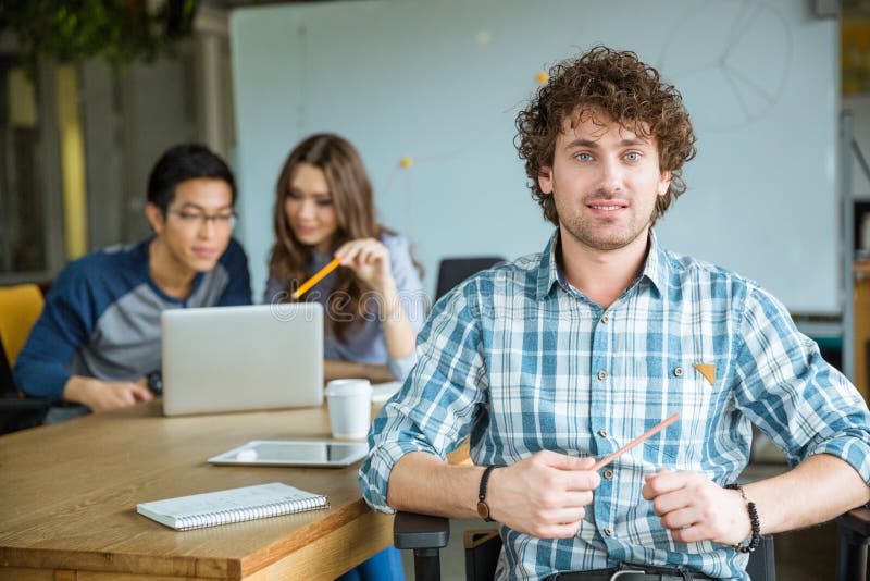 Attraktiv gladlynt ung lockig malestudying med studenter i klassrum royaltyfri foto Attraktiv gladlynt ung lockig malestudying med studenter i klassrum royaltyfri foto
