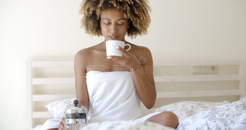 Attraktiv kvinna med en kopp kaffe på sängen royaltyfri fotografi