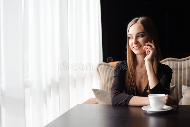 Attraktiv kvinnlig med det gulliga leendet som har talande konversation med mobiltelefonen, medan vila i kafé royaltyfria bilder Attraktiv kvinnlig med det gulliga leendet som har talande konversation med mobiltelefonen, medan vila i kafé royaltyfria bilder