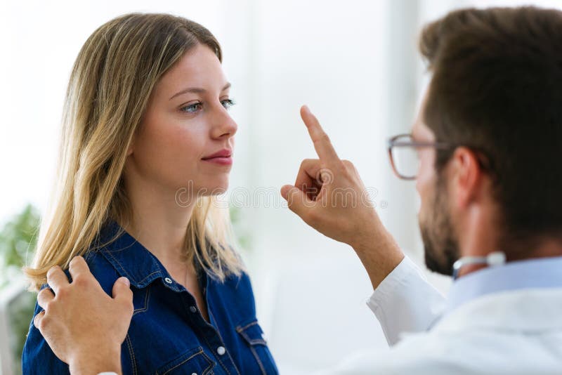Attraktiv manlig doktorsophtalmologist som kontrollerar ögonvisionen av den härliga unga kvinnan i modern klinik arkivfoto Attraktiv manlig doktorsophtalmologist som kontrollerar ögonvisionen av den härliga unga kvinnan i modern klinik arkivfoto