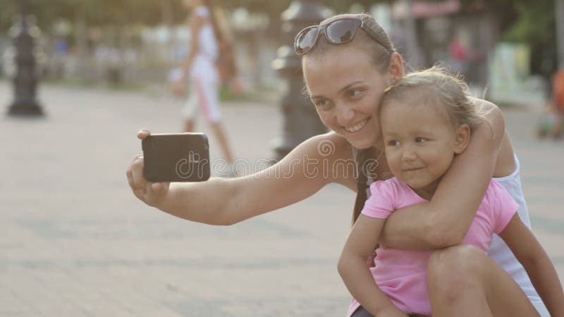 Attraktiv moder och gullig liten dotter som har roligt och gör selfie