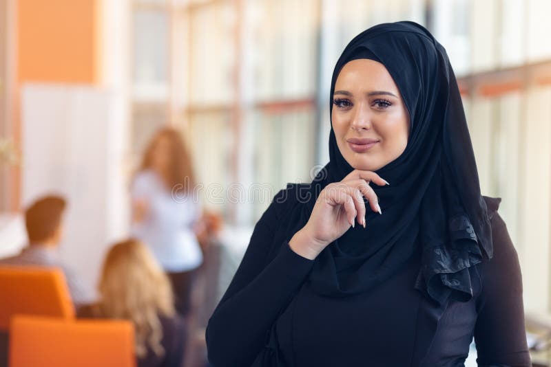 Attraktiv stående av den unga muslimkvinnan med svart hijab på kontoret royaltyfri bild Attraktiv stående av den unga muslimkvinnan med svart hijab på kontoret royaltyfri bild