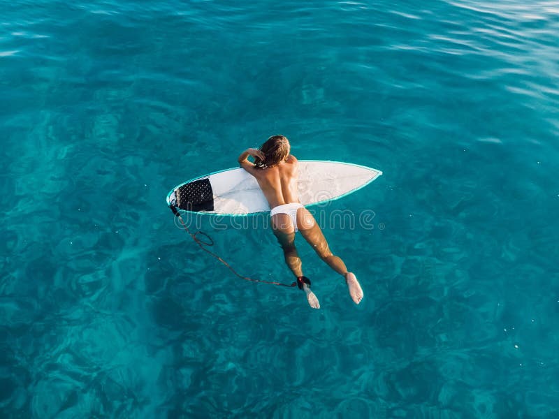 Attraktiv surfkvinna som slappnar av på surfbräda i havet. flygvy med surfflicka