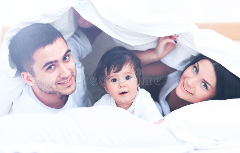 Attraktiv ung familj i sovrummet fotografering för bildbyråer Attraktiv ung familj i sovrummet fotografering för bildbyråer