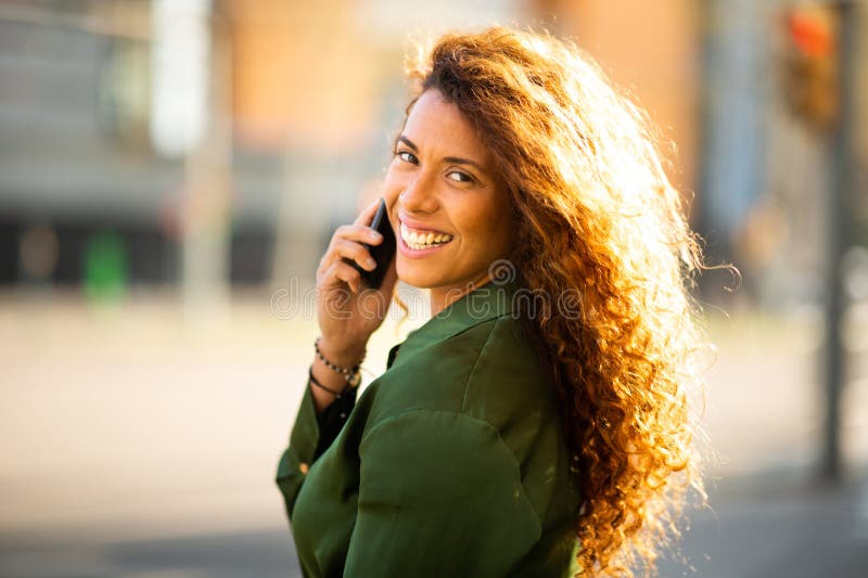 Attraktiv ung latinkvinna som använder mobiltelefon utanför royaltyfri foto